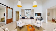 Located at 267 Grand Cypress Road in Summerville, SC, this single-story community clubhouse offers a thoughtfully designed gathering space finished with a coastal-inspired aesthetic throughout. The grand entrance greets visitors with soaring ceilings, floor-to-ceiling gridded windows, and terrazzo flooring that carries throughout the building, flooding the space with natural light and views of the surrounding community.

The reception area serves as the heart of the clubhouse, featuring a chevron-paneled front desk beneath dramatic oversized pendant lights with warm gold interiors. A live-edge wood coffee table and paired lounge chairs create an inviting seating vignette in front of the desk.

Adjacent lounge areas are anchored by a striking sage-green paneled accent wall with brass detailing and a large wall-mounted television, complemented by woven rattan pendant lights and plush, neutral furnishings accented with coastal-toned throw pillows. A dedicated business center offers a row of workstations along a built-in wood desk beneath stylish wall sconces, alongside a shuffleboard table for recreation.

A private meeting room features a large rectangular dining table with upholstered seating, abundant natural light, and curated artwork. Patterned wallcovering lines the connecting corridor, adding texture and visual interest. The overall ambiance is warm, refined, and welcoming.