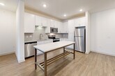 Located at 1521 Lee Rd in Douglasville, GA, this well-appointed 2-bedroom, 2-bathroom single-floor residence offers a thoughtfully designed open-concept layout. The living and kitchen areas flow seamlessly together, anchored by warm wood-look flooring and recessed lighting throughout. The kitchen is a standout feature, equipped with crisp white shaker cabinetry, a classic subway tile backsplash, granite countertops, stainless steel appliances including a dishwasher, range, microwave, and refrigerator, and a central island that provides additional prep and dining space. A ceiling fan in the living area and access to a window-facing exterior complete the communal space. Both bedrooms are carpeted and filled with natural light from large windows, each equipped with ceiling fans for comfort. The primary bedroom is generously sized and includes a walk-in closet with wire shelving. The bathrooms feature white cabinetry with granite countertops and marble-style tile accents. A dedicated in-unit laundry room houses a full-size washer and dryer. Two closets and a hallway round out the layout, offering practical storage throughout this clean, modern home.