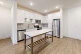 Located at 1521 Lee Rd in Douglasville, GA, this well-appointed 2-bedroom, 2-bathroom single-floor residence offers a thoughtfully designed open-concept layout. The living and kitchen areas flow seamlessly together, anchored by warm wood-look flooring and recessed lighting throughout. The kitchen is a standout feature, equipped with crisp white shaker cabinetry, a classic subway tile backsplash, granite countertops, stainless steel appliances including a dishwasher, range, microwave, and refrigerator, and a central island that provides additional prep and dining space. A ceiling fan in the living area and access to a window-facing exterior complete the communal space. Both bedrooms are carpeted and filled with natural light from large windows, each equipped with ceiling fans for comfort. The primary bedroom is generously sized and includes a walk-in closet with wire shelving. The bathrooms feature white cabinetry with granite countertops and marble-style tile accents. A dedicated in-unit laundry room houses a full-size washer and dryer. Two closets and a hallway round out the layout, offering practical storage throughout this clean, modern home.