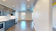 Located at 404 Industrial St in Denton, TX, this thoughtfully designed single-story space offers a clean, modern aesthetic with a practical and open layout. The combined kitchen and living area serves as the heart of the unit, featuring polished concrete floors that reflect natural light streaming in through multiple windows. A ceiling fan adds comfort to the living space, which maintains a bright, airy feel with crisp white walls and recessed lighting throughout.

The kitchen is a standout feature, outfitted with bold slate-blue shaker cabinetry, white quartz countertops, a subway tile backsplash, and a full suite of stainless steel appliances including a refrigerator, electric range, microwave, and dishwasher. The galley-style configuration maximizes efficiency without sacrificing style.

A dedicated hallway connects the main living area to the private spaces, which include a well-appointed bathroom featuring a walk-in shower adorned with striking marble-look tile and a mosaic penny-tile floor. The closet provides organized storage with dual hanging rods and shelving on carpeted flooring. An architectural accent — a recessed ceiling detail with warm ambient lighting — adds a distinctive design touch to the space. Overall, the unit presents a refined, contemporary finish ideal for modern living.