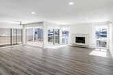 Located along the scenic waterfront of Bayside Cove in Newport Beach, California, this fully updated single-floor residence offers a bright, modern aesthetic with thoughtfully curated finishes throughout. Light-toned hardwood flooring flows seamlessly across every room, tying together a cohesive and airy coastal design.

The expansive living area is a standout, featuring large sliding glass doors and windows that frame stunning marina views and flood the space with natural light. A sleek marble-surround fireplace serves as an elegant focal point, while recessed lighting adds a polished finish overhead.

The kitchen is well-appointed with white shaker cabinetry, brushed gold hardware, quartz countertops with bold veining, a subway tile backsplash, and a full suite of stainless steel appliances including a refrigerator, range, microwave, and dishwasher. A generous peninsula provides additional prep and seating space.

A secondary living or flex space includes a built-in wet bar with a beverage refrigerator, accented by a herringbone mosaic tile backsplash and ceiling fan — ideal for entertaining. Bedrooms are well-proportioned and feature ceiling fans and natural light.

Bathrooms are finished with marble-look quartz vanities, white cabinetry with brushed gold hardware, and glass-enclosed showers. One bathroom includes a soaking tub combo. Sliding doors throughout the space open to views of the Newport Beach marina, completing this refined coastal retreat.