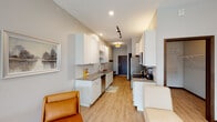 This single-floor studio is thoughtfully designed to maximize functionality within an open, contemporary layout. The main living area is generously proportioned, featuring light hardwood-style flooring, recessed lighting, and a ceiling fan that contributes to the airy atmosphere. Large windows flood the space with natural light, and a sliding glass door leads to a private balcony, offering outdoor views. The living and sleeping areas share one open, flexible space, providing a clean, uncluttered feel well-suited for everyday living.

The galley-style kitchen runs along one wall and is equipped with white cabinetry extending to the ceiling, gray stone countertops, stainless steel appliances including a refrigerator, dishwasher, and microwave, and a dedicated countertop workspace for small appliances. Track lighting and recessed fixtures illuminate the kitchen corridor efficiently.

A walk-in closet with built-in shelving and hanging rods provides ample organized storage. The bathroom features wood-look tile flooring, large-format stone tile wainscoting along the walls, a tub-shower combination, and a vanity with white cabinetry. The overall palette of neutral grays and whites creates a cohesive, modern ambiance throughout.