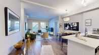 This thoughtfully laid-out 2-bedroom, 1-bathroom residence offers a cohesive open-concept design that maximizes every square foot. Hardwood-style flooring flows throughout the main living area, tying together the kitchen, dining, and living spaces in a seamless and functional arrangement.

The kitchen is a standout feature, boasting white cabinetry, stainless steel appliances, and a generous waterfall-edge breakfast bar with seating for multiple guests — ideal for both casual dining and entertaining. A pendant light fixture above the island adds a polished finishing touch. The adjoining living room is bright and inviting, with a sliding door that opens to an outdoor patio area, allowing for excellent natural light and easy indoor-outdoor flow.

Both bedrooms are comfortably proportioned, with the primary bedroom offering a calm, neutral aesthetic and hardwood-style flooring. Each room benefits from windows fitted with blinds that provide natural light and privacy. The full bathroom features a clean, white tub-shower combination. A dedicated in-unit laundry area with a front-loading washer adds everyday convenience. The overall ambiance is modern and bright, with a neutral color palette of soft grays and whites that lends a clean, contemporary feel throughout.