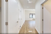 Located at 141 South Harrison Street in East Orange, NJ, this thoughtfully designed unit offers a clean, modern aesthetic across a single level. The open-plan kitchen and living area serves as the heart of the space, featuring warm wood-look flooring that flows seamlessly throughout. The kitchen is outfitted with stainless steel appliances — including a refrigerator, range, microwave, and dishwasher — complemented by two-tone cabinetry with high-gloss white upper cabinets and wood-grain lower cabinets, and a marble-look tile backsplash with matching countertops. Recessed lighting and large windows allow natural light to fill the living area, which also includes a wall-mounted HVAC unit for climate control. The bathroom is a standout feature, showcasing a floating wood-toned vanity with a backlit mirror, a full soaking tub, and striking geometric stone-tile wall accents. A dedicated closet provides convenient storage, and an in-unit laundry area adds everyday practicality. Bright white walls and clean lines throughout give the space a fresh, contemporary feel, making it a well-appointed and functional residence.