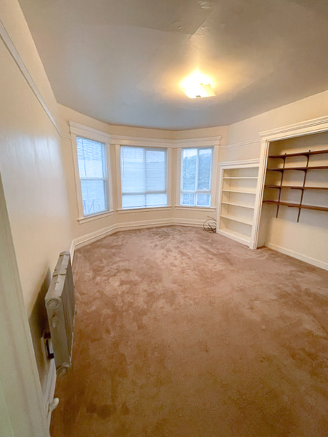 Main living room with built-in shelving and a bay window - 1017 Hyde St