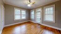 Located at 31 S McLean Blvd in Memphis, TN, this single-story 2-bedroom, 1-bathroom home offers a well-organized layout with a living room, dining room, kitchen, hallway, and four closets. Rich hardwood floors flow throughout the main living areas and bedrooms, complemented by crisp white baseboards and crown molding that add a classic architectural touch. Each bedroom is fitted with a ceiling fan and features multiple windows dressed with blinds, filling the rooms with natural light. The primary bedroom is generously sized, offering ample space and access to closet storage. The kitchen is appointed with warm wood cabinetry, granite countertops, a stainless steel sink, and a dishwasher, with tile flooring and windows providing a bright workspace. The bathroom is a standout feature, showcasing white subway tile on the walls and surround, a classic black-and-white mosaic tile floor, and a full tub-shower combination with chrome fixtures. A central hallway with gleaming hardwood floors connects the rooms efficiently. Neutral gray-toned walls throughout the home create a cohesive, inviting ambiance well-suited to a variety of interior styles.
