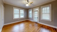 Located at 31 S McLean Blvd in Memphis, TN, this single-story 2-bedroom, 1-bathroom home offers a well-organized layout with a living room, dining room, kitchen, hallway, and four closets. Rich hardwood floors flow throughout the main living areas and bedrooms, complemented by crisp white baseboards and crown molding that add a classic architectural touch. Each bedroom is fitted with a ceiling fan and features multiple windows dressed with blinds, filling the rooms with natural light. The primary bedroom is generously sized, offering ample space and access to closet storage. The kitchen is appointed with warm wood cabinetry, granite countertops, a stainless steel sink, and a dishwasher, with tile flooring and windows providing a bright workspace. The bathroom is a standout feature, showcasing white subway tile on the walls and surround, a classic black-and-white mosaic tile floor, and a full tub-shower combination with chrome fixtures. A central hallway with gleaming hardwood floors connects the rooms efficiently. Neutral gray-toned walls throughout the home create a cohesive, inviting ambiance well-suited to a variety of interior styles.