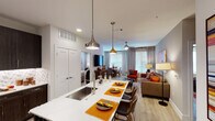 Located in Trophy Club, Texas, this single-story residence offers a thoughtfully designed open-concept layout that seamlessly connects the kitchen, dining, and living areas. The kitchen is a standout feature, equipped with rich dark-espresso cabinetry, stainless steel appliances, a mosaic tile backsplash, and a generous white quartz island with an undermount sink, pendant lighting, and bar seating — ideal for both casual dining and entertaining. The open living and dining area is bathed in natural light from large windows dressed with elegant floor-length drapes, and features light hardwood-style flooring throughout, a ceiling fan, and ample room for comfortable furnishings. The bedrooms are serene and well-sized, each benefiting from natural light through large windows and neutral tones that create a calm, restful atmosphere. The bathrooms are finished with dark wood vanities, white quartz countertops, and large-format tile, with one featuring a soaking tub and the other a shower. Both bathrooms provide direct access to spacious walk-in closets with built-in shelving and hanging systems, offering generous storage. The overall design balances modern finishes with warm, inviting tones throughout.