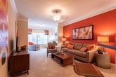 Located at 1644 Bass Rd in Macon, Georgia, this single-floor residence offers a thoughtfully designed layout that balances comfort and functionality across its key living areas. The living room makes an immediate impression with its bold terra-cotta accent wall, crown molding, and plush carpeting, creating a warm and inviting atmosphere. The space flows naturally into a versatile sitting or flex area, well-lit by multiple windows dressed with decorative curtains that allow ample natural light. The kitchen features white cabinetry, dark countertops, a peninsula with bar seating, and wood-look flooring, providing both practicality and style. Adjacent to the kitchen, the dining area accommodates a round table beneath a classic chandelier, complemented by decorative wall mirrors that enhance the sense of space. The bedroom is a restful retreat with soft carpet, generous natural light from French doors leading to an outdoor area, and a ceiling light fixture. A walk-in closet with built-in wire shelving offers substantial storage capacity. The bathroom includes a white vanity with ample drawer space, a well-lit mirror, and durable wood-look flooring. Throughout the residence, a cohesive warm neutral palette with orange accents ties each room together into a harmonious and comfortable living environment.