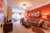 Located at 1644 Bass Rd in Macon, Georgia, this single-floor residence offers a thoughtfully designed layout that balances comfort and functionality across its key living areas. The living room makes an immediate impression with its bold terra-cotta accent wall, crown molding, and plush carpeting, creating a warm and inviting atmosphere. The space flows naturally into a versatile sitting or flex area, well-lit by multiple windows dressed with decorative curtains that allow ample natural light. The kitchen features white cabinetry, dark countertops, a peninsula with bar seating, and wood-look flooring, providing both practicality and style. Adjacent to the kitchen, the dining area accommodates a round table beneath a classic chandelier, complemented by decorative wall mirrors that enhance the sense of space. The bedroom is a restful retreat with soft carpet, generous natural light from French doors leading to an outdoor area, and a ceiling light fixture. A walk-in closet with built-in wire shelving offers substantial storage capacity. The bathroom includes a white vanity with ample drawer space, a well-lit mirror, and durable wood-look flooring. Throughout the residence, a cohesive warm neutral palette with orange accents ties each room together into a harmonious and comfortable living environment.