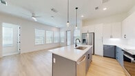 Located at 4220 Tributary Way in Frisco, TX, this thoughtfully designed single-story home offers 2 bedrooms and 3 bathrooms across a well-appointed floor plan. The heart of the home is an open-concept living, dining, and kitchen area bathed in natural light from a generous bank of windows. Light hardwood flooring flows throughout the main living areas, complementing the bright, neutral palette. The modern kitchen is anchored by a large center island with a white quartz countertop, dual-tone cabinetry featuring crisp white uppers and cool gray lowers, stainless steel appliances, and sleek pendant lighting. The living area opens to an outdoor access point, enhancing the airy feel. The primary bedroom features plush carpeting and connects directly to a well-appointed en-suite bath with a double vanity, white shaker cabinetry, matte black hardware, a large mirror, and a walk-in shower. A spacious walk-in closet with multi-level shelving and hanging rods provides ample storage. The second bedroom is equally comfortable with soft carpet and its own nearby bathroom. A dedicated laundry room, utility room, and additional closet space round out this clean, contemporary home.
