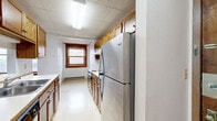 Located at 10 Seventh St S in Fargo, North Dakota, this one-bedroom, one-bathroom unit offers a functional and straightforward layout across a single floor. The galley-style kitchen is well-equipped, featuring warm wood cabinetry, a stainless steel refrigerator, an electric range, and light vinyl flooring. A drop-tile ceiling and a wood-trimmed window provide natural light to the space. The bedroom offers comfortable proportions, with plush carpeting, a built-in closet with wood bifold doors, and multiple wood-trimmed windows that allow ample natural light to fill the room. Baseboard heating is present throughout the unit, ensuring consistent warmth. The living area is open and carpeted, with white walls and neutral tones that create a clean, simple ambiance. A wood-accented cabinet adds a touch of warmth to the space. The bathroom features a full tub-shower combo with a clean white surround, providing a simple and practical design. Consistent warm wood trim details on windows and doors are found throughout, tying the unit together with a classic, cohesive character well-suited for comfortable everyday living in Fargo.
