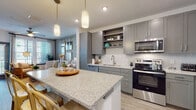 Located at 7200 N Frontage Rd in Orlando, FL, this single-floor residence offers a thoughtfully designed layout with contemporary finishes throughout. The open-concept kitchen is a standout feature, equipped with stainless steel appliances including a range, microwave, dishwasher, and refrigerator. Gray shaker-style cabinetry, granite countertops, a herringbone tile backsplash, and a generous kitchen island with pendant lighting make this space as functional as it is visually appealing. Light wood-style flooring runs throughout, contributing to a cohesive and modern aesthetic. The living area is bright and welcoming, with large windows that allow abundant natural light and provide outdoor views. A ceiling fan adds comfort to the space. The bedroom is well-sized, featuring large windows, wood-style flooring, and a calm, neutral color palette. A dedicated walk-in closet offers built-in shelving for organized storage. The bathroom is finished with matching granite countertops, gray cabinetry, a large vanity mirror, and marble-style tile flooring and surround, creating a clean and polished look. Overall, the residence presents a modern, cohesive design with quality finishes and a comfortable, functional flow.
