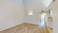 Located at 2901 Euclid Ave NE in Albuquerque, New Mexico, this one-bedroom, one-bathroom unit offers a thoughtfully laid-out single-floor plan. The combined kitchen and living room area forms the heart of the home, highlighted by striking vaulted ceilings that lend an open, airy feel. Light wood-look flooring runs throughout the living spaces, complementing the bright white walls and allowing natural light to flow freely. Large sliding glass doors in the living area open to a private balcony, providing pleasant outdoor views of surrounding greenery. The kitchen is efficiently designed with ample white cabinetry, tile countertops, a warm tile backsplash, and white appliances including an electric range and dishwasher. A hallway connects the living spaces to the generously sized bedroom, which features a built-in closet with sliding doors, a wall sconce, and the same wood-look flooring. The full bathroom is well-appointed with a long vanity, light cabinetry, tile flooring, and a tub-shower combination accented by warm earth-toned tile surrounds. The overall ambiance of the unit is clean, bright, and functional, making it a comfortable residence in the heart of Albuquerque.