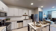 Located at 1430 Woerner Ave in Clarksville, Indiana, this well-appointed single-floor residence offers a thoughtfully designed layout with modern finishes and a clean, contemporary aesthetic throughout. The kitchen is a standout feature, showcasing white shaker-style cabinetry with black hardware, a white subway tile backsplash, quartz countertops, and a full suite of stainless steel appliances including a refrigerator, dishwasher, microwave, and range. A decorative floating wood shelf adds a warm accent to the otherwise crisp, neutral palette. Light wood-style flooring runs throughout the space, enhancing the bright and airy feel. The living area benefits from large windows and a glass-panel door that invites abundant natural light, creating an open and welcoming atmosphere. The bedroom is a calm retreat, featuring a generously sized window with sheer draping that diffuses soft natural light, complemented by warm, neutral tones and light flooring. The bathroom is finished with a wide vanity topped with stone-look counters, a black-framed mirror, matte black fixtures, and a glass-enclosed shower, delivering a clean and modern spa-like feel. Dark-framed doors and accent trim provide a striking contrast against the light walls, tying the contemporary design together cohesively across the entire space.