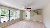 Located at 5122 SE Lisbon Cir in Stuart, FL, this two-story home offers 2 bedrooms and 3 bathrooms across two well-proportioned floors. The main level hosts the kitchen and living room, while the upper floor is dedicated to the bedrooms and additional bathrooms.

The kitchen is a standout feature, showcasing gray shaker-style cabinetry, granite countertops, white tile flooring, and a peninsula that provides extra counter space and casual dining potential. White appliances, including a refrigerator and electric range, complete the functional layout.

The living room is bright and welcoming, with large windows dressed in vertical blinds that frame views of the surrounding greenery, complemented by plush carpeting and a ceiling fan overhead.

Both bedrooms are generously proportioned and carpeted, each featuring ceiling fans for year-round comfort. The spacious primary bedroom offers dual closets with louvered bifold doors. The bathrooms are clean and well-appointed, with one featuring a tiled tub-shower combination and another boasting a wide vanity with granite countertops and gray cabinetry.

A private balcony provides pleasant views of the landscaped grounds, mature palm trees, and the quiet residential surroundings typical of Stuart's warm Florida setting.