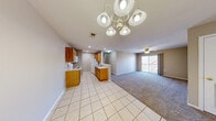 Located at 2650 N Barnes Ave in Springfield, Missouri, this single-floor, 2-bedroom, 2-bathroom home offers a practical and comfortable layout. The open-concept living area seamlessly connects the living room, dining area, and kitchen, creating a spacious, cohesive feel. The living room is carpeted and features a ceiling fan and a sliding glass door that brings in natural light and provides outdoor access. The kitchen is equipped with warm honey-toned wood cabinetry, white appliances including a range, microwave, and refrigerator, and light ceramic tile flooring. A peninsula-style counter separates the kitchen from the dining area, which is accented by a decorative chandelier. A pantry provides additional storage nearby. The primary bedroom is generously sized, carpeted, and includes a ceiling fan and a walk-in closet with wire shelving. The second bedroom is also carpeted with a ceiling fan and a window for natural light. Both bathrooms feature clean white fixtures — one with a stand-up shower and one with a soaking tub. Additional highlights include a hallway with an electrical panel, three closets throughout, a dedicated laundry room, and a utility room. Warm wood-toned trim and neutral tones create a cohesive look throughout the home.