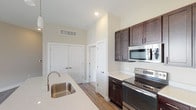 This well-appointed single-floor residence offers a thoughtfully designed layout with modern finishes throughout. The open-concept kitchen serves as the heart of the home, showcasing rich dark espresso cabinetry with sleek brushed nickel hardware, light quartz countertops, and a full suite of stainless steel appliances including an electric range, built-in microwave, and French door refrigerator. A generously sized center island with an undermount sink and elegant pendant lighting above makes the kitchen both functional and visually striking. Wood-style flooring runs throughout the main living and kitchen areas, adding warmth and continuity.

The living area features durable hardwood-style flooring, a sliding glass door with vertical blinds, and multiple windows that fill the space with natural light and outdoor views. The bedrooms are carpeted for comfort, each equipped with a ceiling fan and windows overlooking the surrounding greenery. The bathrooms are finished with dark vanity cabinetry, quartz countertops, wood-style flooring, and a tub-shower combination in the full bath, along with a dedicated over-toilet storage cabinet in the secondary bathroom. A separate in-unit laundry room with full-size washer and dryer completes this practical and stylish residence.