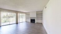 Located in Houston, TX, this 2-bedroom, 3-bathroom single-floor residence offers a well-organized layout designed for comfortable everyday living. The open living room serves as the heart of the home, featuring a classic fireplace flanked by built-in shelving units, wood-look luxury vinyl plank flooring, and large sliding glass doors that flood the space with natural light and open to an outdoor patio with green views. The kitchen is well-appointed with rich dark wood cabinetry, granite-look countertops, a black electric range, and a convenient pantry with double bi-fold doors, all finished with wood-look flooring for a cohesive feel. Both bedrooms are generously sized, carpeted for comfort, and receive natural light through their windows. The spacious primary bedroom connects to the hallway with easy access to the bathrooms. The three bathrooms are cleanly finished, featuring dark wood vanities with granite-look countertops; one bathroom includes a glass-enclosed walk-in shower with white tile surround, while another offers a full tub-shower combination. Hallways connect all areas efficiently, and a dedicated closet adds practical storage. The overall aesthetic is clean, neutral, and move-in ready.