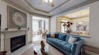 Located at Country Walk in Snellville, GA, this single-floor, two-bedroom, two-bathroom residence offers a well-designed layout with thoughtful architectural details throughout. The open-concept kitchen features white cabinetry, a subway tile backsplash, stainless steel appliances including a refrigerator and range, and a spacious peninsula with a double sink and stone-look countertops — ideal for both cooking and casual dining. Wood-look flooring runs through the kitchen and extends into adjoining areas. The living room impresses with a tray ceiling, ceiling fan, and a classic fireplace, creating a warm and inviting focal point. An adjacent sunlit sitting area with tile flooring and large windows provides a bright, versatile space. The formal dining area is distinguished by wainscoting, crown molding, and an elegant overhead light fixture. Both bedrooms are carpeted and receive ample natural light through large windows with views of surrounding greenery. The bathrooms are clean and functional, with the full bath offering a wide vanity with white cabinetry, a large mirror, and a tub/shower combination. The home also includes an attached garage, adding practical convenience to this comfortable and well-appointed residence.