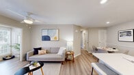 Located at 7100 Claxton Cir in Raleigh, NC, this well-appointed two-bedroom, two-bathroom residence offers a thoughtfully designed single-floor layout. The open-concept living, dining, and kitchen area serves as the heart of the home, bathed in natural light from large windows with plantation-style blinds. The living room features warm luxury vinyl plank flooring, a ceiling fan, and a neutral color palette that creates a bright, welcoming atmosphere. The kitchen is equipped with stainless steel appliances, white shaker cabinetry, a light stone countertop, and a peninsula with an undermount sink — ideal for both cooking and casual dining. The primary bedroom is a comfortable retreat with a ceiling fan, closet access, and an en-suite bathroom featuring a double-sink vanity with white cabinetry, a walk-in shower, and built-in wire shelving for ample storage. The second bedroom offers natural light and versatile space suitable as a guest room or home office. A second full bathroom includes a soaking tub with shower combination. Additional highlights include an in-unit laundry area with a top-load washer, a utility room, a hallway connecting all spaces, and five closets throughout providing generous storage.