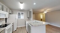 This single-story residence on Oak Branch Lane in Sanford, NC offers a clean, modern interior defined by consistent light wood-style flooring and a neutral gray color palette throughout. The open-concept living and dining area is spacious and bright, featuring a ceiling fan with light fixture, a textured ceiling, and French doors that invite natural light and provide outdoor access. An additional side entry door further connects the interior to the exterior.

The kitchen is efficiently designed with gray cabinetry, granite-look countertops, and white appliances including a refrigerator, electric range, built-in microwave, and dishwasher. A peninsula with an undermount sink and pendant lighting above creates a natural division between the kitchen and the dining area, making it functional for both cooking and casual dining.

The bedrooms are well-proportioned, each equipped with ceiling fans and multiple windows that bring in ample natural light. The bathroom features a gray vanity with granite-look countertop, a large mirror with vanity lighting, and matching flooring that ties into the rest of the unit. The overall ambiance is clean, bright, and move-in ready, reflecting a cohesive and contemporary design throughout.