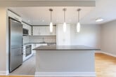Located at 74 Curlew Dr in Toronto's M3A neighbourhood, this well-appointed one-bedroom, one-bathroom unit offers a thoughtfully designed layout across a single floor. Warm hardwood flooring flows throughout the living areas and bedroom, complemented by neutral grey-toned walls that create a clean, modern aesthetic.

The kitchen is a standout feature, showcasing white cabinetry with sleek hardware, grey countertops, a central peninsula with pendant lighting overhead, and stainless steel appliances including a refrigerator, microwave, oven, and dishwasher. White tile flooring grounds the kitchen space, which opens directly into the combined living area.

The living room is bright and airy, benefiting from large windows that frame lush treetop views and allow generous natural light to fill the space. Baseboard heating units run along the perimeter walls throughout the unit.

The bedroom is a comfortable size, featuring its own large window with views of the surrounding greenery and a textured ceiling detail that adds subtle character.

The bathroom is finished in a contemporary style with large-format grey wall tiles, a soaker tub with an overhead rain showerhead and handheld fixture, a wall-mounted toilet, and white tile flooring, creating a clean and functional space.
