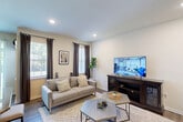Located at 73 Dakota Dr in Hamilton, NJ, this well-appointed home spans three floors and offers generous living space across five bedrooms and three bathrooms. The main level features an open-concept layout where the living room, dining area, and kitchen flow seamlessly together. The living room is bright and welcoming, with multiple windows dressed in elegant drapes that allow natural light to fill the space. A staircase with classic white balusters and dark wood rails anchors the open living and dining area, which is illuminated by a chandelier overhead. The kitchen is a standout, boasting rich dark cabinetry, granite countertops, a tile backsplash, a central island, and stainless steel appliances. Hardwood-style flooring runs throughout the main level, while a clean hallway connects the rooms with ease. The upper floors house the bedrooms, including a generously sized primary bedroom with a closet and recessed lighting. The bathrooms feature elegant tile surrounds with decorative mosaic accents. A dedicated laundry room adds everyday convenience. The attached garage provides secure parking and additional storage. The unfinished basement, with its open concrete walls and exposed framing, presents a blank canvas for customization and extra storage.
