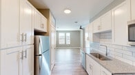 This studio in Birmingham, AL offers a thoughtfully designed single-floor layout that maximizes every square foot. The open-concept kitchen and living area serves as the heart of the space, featuring white shaker cabinetry with brushed gold hardware, granite countertops, a white subway tile backsplash, and stainless steel appliances including a refrigerator, electric range, and over-the-range microwave. Light wood-look flooring flows seamlessly throughout, complementing the soft gray-green wall tones that lend a calm, modern ambiance. The living area benefits from natural light through a window, enhanced by a ceiling fan overhead. Two closets provide ample storage for a studio layout. The unit includes two bathrooms, with one conveniently housing a stacked in-unit washer and dryer alongside a vanity with granite countertops. Clean white shaker-style interior doors and crisp white trim add a polished finishing touch throughout. The overall design balances functionality with contemporary style, creating an efficient yet comfortable living environment in the heart of Birmingham.