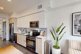 Located at 501 NW Seventh Terrace in Fort Lauderdale, FL, this thoughtfully designed one-bedroom, one-bathroom unit offers a compact yet efficient single-floor layout with modern finishes throughout. The open-concept living, dining, and kitchen area serves as the heart of the home, anchored by large floor-to-ceiling windows that flood the space with natural light and frame views of the surrounding neighborhood and Fort Lauderdale skyline. The kitchen features sleek, flat-panel cabinetry in a warm wood tone paired with white upper cabinets, stainless steel appliances, a subway tile backsplash, and clean white countertops. Wide-plank wood-look flooring runs throughout, adding warmth and continuity. A hallway connects the living area to the private bedroom, which includes a sliding double-panel closet and a cozy, well-proportioned layout. The bathroom is finished with large-format gray wall tiles, a soaking tub with shower, a floating wood vanity, and white countertops, giving it a clean, spa-inspired feel. Additional features include two closets, an in-unit laundry area, and recessed lighting throughout. The overall aesthetic is crisp, contemporary, and efficiently organized.