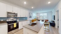 Located at 72 Milton Ave SE in Atlanta's Grant Park area, this single-floor residence showcases a clean, contemporary design with an emphasis on open living. The heart of the home is a sleek, open-concept kitchen and living area bathed in natural light from large windows. The kitchen is outfitted with white shaker cabinetry, a blue tile backsplash, quartz countertops, stainless steel appliances, and a central island with seating — ideal for both cooking and casual dining. Light wood-style flooring flows seamlessly from the kitchen into the living area, which features multiple oversized windows offering neighborhood views and an abundance of natural light. The living room provides ample space for comfortable seating and entertainment. Both bedrooms are carpeted for warmth and comfort, each featuring large windows dressed with blinds and curtains, and generous space for furnishings. The bathroom is bright and well-appointed, featuring a floating vanity with quartz counters, a large mirror, and a tub-shower combination, with direct access to one of the bedrooms. Recessed lighting throughout maintains a modern, airy ambiance. This residence combines thoughtful design with practical amenities in a well-connected Atlanta neighborhood.
