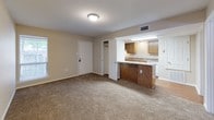 This single-floor unit is designed with functionality and comfort in mind, featuring a cohesive layout that connects the main living areas efficiently. The kitchen is equipped with warm oak cabinetry offering generous storage above and below the counter, complemented by granite-patterned laminate countertops, a stainless steel sink, and a coil-burner electric range with an overhead exhaust hood. Durable wood-look flooring runs throughout the kitchen, adding a clean, practical finish to the space.

The living area is open and carpeted with neutral-toned flooring, receiving abundant natural light through a large sliding glass door fitted with vertical blinds that offer both privacy and outdoor views. A peninsula counter connects the kitchen to the living space, creating a semi-open floor plan that enhances the sense of flow between areas. An entry closet provides additional storage near the front door.

The bedrooms are carpeted and finished with neutral walls, offering versatile spaces suitable for various furniture arrangements. Ceiling-mounted light fixtures illuminate each room. The bathroom features wood-look flooring, a white tub-shower combination, a toilet, and recessed overhead lighting, maintaining a clean and functional design throughout.