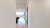 Located at 550 Westlake Park Blvd in Houston's Energy Corridor, this well-appointed 2-bedroom, 2-bathroom residence offers a thoughtfully designed single-floor layout with modern finishes throughout. Light wood flooring flows seamlessly across the main living areas, complementing the clean, contemporary aesthetic.

The open-concept kitchen is a standout feature, showcasing a two-tone cabinetry design that pairs warm wood lower cabinets with crisp white upper cabinets, all accented by matte black hardware. Quartz countertops, a center island with bar seating, stainless steel appliances, and stylish pendant lighting complete this well-equipped space.

The living room is bathed in natural light through large floor-to-ceiling windows with black-framed trim, offering treetop views that bring a sense of the outdoors in. Soaring ceilings with exposed beams add architectural character and an airy, open feel.

The generously sized primary bedroom features carpeted flooring, large windows with outdoor views, and access to a spacious walk-in closet with extensive built-in shelving and hanging rods. The en-suite bathroom is finished with wood-toned vanity cabinetry, white countertops, and a glass-enclosed walk-in shower. The second bathroom offers a full tub-shower combination with tile surround and matching modern finishes.