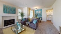 This single-floor residence is thoughtfully laid out to maximize functionality and comfort throughout. The living area serves as the heart of the home, anchored by a white tile-surround fireplace and framed by multiple windows that bring in generous natural light. The space flows seamlessly into a dedicated dining area, which is set against a bold teal accent wall with built-in display shelving, adding both character and storage. Adjacent to the dining space, the kitchen features white cabinetry, stone-look countertops, a double basin sink, and includes a dishwasher, with a window above the sink providing additional brightness.

The bedroom is generously proportioned with plush carpeting, multiple windows offering ample natural light, and a warm, neutral palette. A hallway connects the living spaces to the bedroom and bathroom, which features wood-style flooring, a long white vanity with dual sinks, a large mirror, and a separate bathtub. A walk-in closet with built-in shelving provides substantial storage. Throughout the residence, neutral wall tones are accented with teal and gold color touches, creating a cohesive and inviting ambiance.
