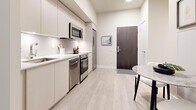 Located at 26 Tippett Rd in Toronto's Clanton Park neighbourhood, this efficiently designed one-bedroom, one-bathroom unit makes excellent use of its space across a single floor. Light wood-look flooring runs throughout, lending a clean, cohesive aesthetic that brightens each room.

The open-concept kitchen and living area form the heart of the unit. The kitchen is outfitted with flat-front white cabinetry, a white quartz countertop, subway tile backsplash, and a full suite of stainless steel appliances including a refrigerator, electric range, built-in microwave, and dishwasher. A compact dining area with a round marble-topped table sits adjacent, maximizing the available floor space.

The living area benefits from floor-to-ceiling windows and a glass door that opens directly to a private outdoor space, flooding the interior with natural light and providing lush green views of surrounding landscaping. A tray ceiling detail adds a subtle architectural touch overhead.

The bedroom is a comfortable retreat featuring direct access to the same private outdoor area, a mirrored sliding closet, and soft natural light filtered through roller blinds. The bathroom is finished with large-format floor tiles, beige subway wall tiles in the tub surround, a floating vanity with an undermount sink, and in-unit laundry is also accommodated within this space.