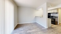 Located at 550 S Camino Seco in Tucson, Arizona, this efficiently designed single-floor unit makes smart use of its compact footprint. Wood-look plank flooring flows throughout the space, providing a cohesive and modern aesthetic. The combined kitchen and living area forms the heart of the unit. The kitchen is equipped with white cabinetry, speckled granite-style countertops, a stainless steel sink, and black appliances including a refrigerator, electric range, and dishwasher. A pass-through counter with a built-in shelf connects the kitchen to the living area, enhancing the open feel. The living room is bathed in natural light thanks to a full-width sliding glass door fitted with vertical blinds, which provides an inviting view to the outdoors. Soft blue-gray walls and a chandelier accent the dining area, adding a touch of warmth and character. The bathroom is conveniently accessible from the main living space, and a dedicated closet offers practical storage. The textured ceilings and clean white trim throughout contribute to a bright, well-maintained interior. Overall, this unit presents a functional and neatly updated layout well-suited for efficient single-floor living in Tucson.