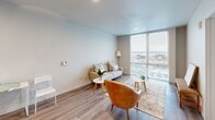 Located at 513 1st Ave N in Seattle's Lower Queen Anne neighborhood, this thoughtfully designed one-bedroom, one-bathroom unit offers a clean, modern aesthetic throughout. Light wood-tone flooring flows continuously across the open-plan living and kitchen area, creating a cohesive and airy feel. The kitchen is well-appointed with two-tone cabinetry—natural wood uppers paired with dark lower cabinets—set against a white tile backsplash and white countertops. Stainless steel appliances, including a range, microwave, dishwasher, and refrigerator, complete the space. The living room is anchored by floor-to-ceiling windows that frame sweeping views of Puget Sound and the Seattle skyline, flooding the space with natural light. The bedroom also benefits from city and water views through a large window, and features a sliding-door closet. A dedicated den provides a flexible workspace or secondary room. The bathroom includes a full tub-shower combo, dark vanity cabinetry with a white countertop, and matching hardware finishes. Additional storage is provided by multiple closets, and an in-unit laundry area adds everyday convenience. Recessed lighting throughout lends a polished, contemporary finish to this well-organized urban residence.