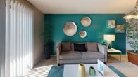 This single-floor residence offers a thoughtfully designed layout that balances comfort and style across its key living areas. The living room makes a bold visual statement with a striking teal accent wall adorned with decorative metallic disc art, complemented by plush carpeting and an abundance of natural light. Adjacent to the living area, a dedicated dining nook features a round dark-wood table with modern wire-frame chairs and a window with horizontal blinds, creating an intimate yet functional space for meals. The kitchen is outfitted with rich dark cabinetry, light stone-look countertops, a double stainless steel sink, a mirrored backsplash that amplifies natural light, and a built-in dishwasher. The primary bedroom offers a cozy retreat with soft carpeting, louvered bi-fold closet doors, and warm ambient lighting. The second bedroom is bright and airy, featuring sliding glass doors that open to a balcony with outdoor views, carpeted floors, and a white dresser with mirror. The bathroom includes a vanity with dark cabinetry, tile flooring, a walk-in closet with wire shelving, and a full tub-shower combination finished with clean white tile. Throughout the space, textured ceilings and neutral warm-toned walls provide a cohesive, welcoming ambiance.