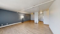 Located at 4917 Thunderbird Dr in Boulder, CO, this single-floor, two-bedroom, one-bathroom residence offers a practical and comfortable layout. The open living room is a standout feature, showcasing light wood-style flooring, a bold blue accent wall, exposed overhead pipe details, and large windows with vertical blinds that invite generous natural light. A wall-mounted A/C unit and baseboard heating provide year-round comfort. The kitchen is thoughtfully designed with a striking dark wood pass-through counter, white surfaces, and a full suite of appliances, creating a clean, modern aesthetic. Both bedrooms are carpeted and offer a quiet, neutral palette with ample closet space featuring bifold doors with built-in hanging rods. The primary bedroom includes a window with natural light and baseboard heating. The bathroom is clean and functional, featuring a dark wood vanity with a white countertop, a medicine cabinet mirror, and light tile flooring. A connecting hallway leads efficiently between the living area, bedrooms, and bathroom. Four closets throughout the unit provide excellent storage. The overall ambiance is clean, understated, and well-suited for comfortable everyday living in Boulder.