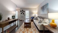 Located at 1225 Boone Hill Rd in Summerville, SC, this single-floor residence offers a thoughtfully arranged layout with a welcoming flow throughout. The living room serves as the heart of the home, featuring rich hardwood-style flooring, a front-facing door with glass panels that invite natural light, and ample space for comfortable seating. Adjacent to the living area is a dedicated dining space, complete with a round wood-top table beneath a stylish pendant light fixture and decorative metal wall art, adding character to the room. The galley-style kitchen is efficiently designed with white cabinetry lining both sides, wood-look flooring, a double sink, and full appliances including a range and refrigerator, with a louvered closet door providing additional storage access. The residence includes multiple bedrooms, each carpeted and filled with natural light from well-positioned windows. One bedroom offers a particularly bright corner layout with views of surrounding greenery, while another features a private en-suite bathroom. The bathrooms are clean and functional, with one showcasing a full tub-shower combination and wood-look tile flooring. Neutral gray tones throughout the walls create a cohesive and modern backdrop across all rooms.