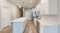 Located at 507–509 Stone Haven Dr NE in Byron, Minnesota, this well-appointed two-story home offers 3 bedrooms and 3 bathrooms across two thoughtfully designed floors. The main level features an open-concept layout connecting the kitchen, dining, and living areas, creating a bright and welcoming atmosphere. The kitchen is a standout, showcasing crisp white shaker cabinetry, striking quartz countertops with subtle veining, a central island with pendant lighting, and a full suite of stainless steel appliances including a gas range, built-in microwave, and dishwasher. Warm luxury vinyl plank flooring runs throughout both levels, lending a cohesive and modern feel. A conveniently located half bath rounds out the main floor. Upstairs, the generously sized primary bedroom offers ample space and is complemented by a dedicated closet with wire shelving for organized storage. Two additional bedrooms each feature windows that invite natural light and views of the outdoors. The upper level also includes a dedicated laundry room with a full-size washer and dryer, adding everyday convenience. Clean neutral walls, recessed lighting, and consistent finishes throughout give this home a fresh, move-in-ready appeal.