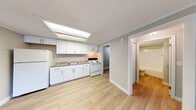 Located at 13809 Heron Wood Lane in Fort Myers, Florida, this single-story unit offers a clean, updated interior with a straightforward, functional layout. Light-toned wood-look flooring runs consistently throughout the space, contributing to a bright and cohesive aesthetic.

The kitchen is well-appointed with white shaker-style cabinetry, granite-look countertops, an undermount sink, and white appliances including a refrigerator and electric range. A large skylight-style overhead fixture provides ample illumination. The kitchen opens directly to the main living area, which is generously proportioned and features a neutral gray color palette, a textured ceiling, and a front entry door with a window that allows natural light into the space.

The bedroom is a comfortable size, equipped with a ceiling fan and a window with blinds. Adjacent to the bedroom is a full bathroom featuring a white vanity, toilet, and a tub-shower combination. A walk-in closet provides convenient storage directly off the main living area. A dedicated utility room houses the water heater and includes washer/dryer connections. The overall ambiance is clean, neutral, and move-in ready.