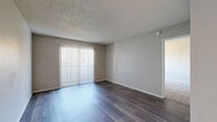 Located at 5400 S Maryland Pkwy in Las Vegas, NV, this 2-bedroom, 1-bathroom residence offers a practical and well-organized single-floor layout. The living room greets you with rich wood-style flooring, neutral gray walls, a textured ceiling, and a sliding glass door with vertical blinds that invite natural light while offering outdoor access. The kitchen is efficiently designed with white cabinetry, granite-style countertops, a skylight panel ceiling fixture, a full suite of appliances including a refrigerator, range, and dishwasher, and a peninsula breakfast bar that opens to the main living area. A carpeted hallway connects the bedrooms and bathroom, with a thermostat conveniently mounted along the corridor. The primary bedroom is generously sized, featuring wood-style flooring, a closet, and a large window with vertical blinds. The second bedroom is carpeted with its own window, providing a comfortable and bright space. The full bathroom includes a tub-shower combination with a curtain rod and a clean white vanity with under-sink storage. A dedicated closet adds practical storage to the unit. The overall aesthetic is clean and neutral, making it a versatile and move-in ready home.