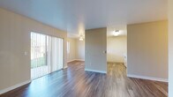 This single-floor residence offers a well-organized layout that connects living, dining, and kitchen areas in an open, functional arrangement. The main living area is anchored by durable wood-style laminate flooring that extends throughout most of the unit, complemented by neutral beige walls and a ceiling fan with light fixture. A full-width sliding glass door fitted with vertical blinds fills the living space with natural light and provides direct access to an outdoor patio area, offering views of the surrounding greenery.

The kitchen is efficiently designed with light wood cabinetry, laminate countertops, and a full suite of white appliances including an electric range, over-the-range microwave, and refrigerator. A pass-through window connects the kitchen to an adjacent dining or flex space, enhancing the sense of openness between rooms.

The bedroom features plush wall-to-wall carpeting, a ceiling fan, a baseboard heater, and a large window dressed with vertical blinds that invite generous natural light. The bathroom area connects to a linen closet with built-in shelving, as well as a dedicated in-unit laundry closet housing a full-size washer and dryer. The overall ambiance is clean, practical, and move-in ready.