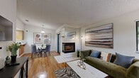 This single-floor, 2-bedroom, 1-bathroom residence in Fremont, CA offers a well-organized layout with wood-style flooring running throughout the main living areas. The open-plan living, dining, and kitchen zone forms the heart of the home. The living room is anchored by a striking white tile-surround fireplace that acts as a visual divider between the living and dining areas, adding architectural character. A sliding glass door leads to a private balcony with views of surrounding greenery, filling the space with natural light. Windows fitted with horizontal blinds further enhance the brightness of the room.

The kitchen features warm honey-toned cabinetry, light countertops, and white appliances, providing a functional and cohesive workspace. The dining area accommodates a round table beneath a pendant light.

The primary bedroom includes a mirrored sliding-door closet with built-in shelving and a window overlooking outdoor greenery. The second bedroom is equally light-filled. The bathroom offers an L-shaped vanity with warm wood cabinetry, a large mirror, and ample counter space. A dedicated laundry area houses a stacked washer and dryer unit. Textured ceilings are present throughout.