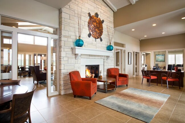 Adéntrate en la acogedora zona común de SunStone at Fox Ridge, donde el diseño contemporáneo se fusiona con la calidez. Disfruta de reuniones junto a la chimenea o relájate en nuestros elegantes sillones. Tu espacio ideal te espera: ¡programa una visita hoy mismo! - SunStone at Fox Ridge