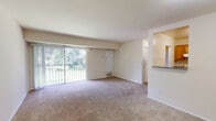 Located in Triangle, VA, this two-bedroom, one-bathroom residence offers a practical and comfortable single-floor layout. The living room serves as the heart of the home, featuring neutral-toned carpet, a large sliding glass door that opens onto a private balcony, and lush green tree views that fill the space with natural light. The open sightlines from the living area connect seamlessly to the kitchen passthrough, enhancing the sense of space.

The kitchen is outfitted with warm oak cabinetry extending to the ceiling for ample storage, gray laminate countertops, a gas range, dishwasher, and refrigerator, all set atop easy-clean tile flooring. A hallway connects the main living areas to the two bedrooms, each finished with plush carpet and neutral walls. The primary bedroom offers generous proportions, a walk-in closet, and an additional door for added flexibility. The second bedroom features a sliding bifold closet and a window with outdoor views. In total, four closets provide excellent storage throughout. The bathroom includes a full tub-shower combination with clean white tile surround and chrome fixtures, offering a simple, functional design. The overall ambiance is light, airy, and move-in ready.