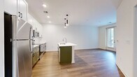 Located at 3939 State Line Rd in Kansas City, MO, this efficiently designed one-bedroom, one-bathroom residence offers a bright and modern living experience across a single floor. The open-concept layout seamlessly connects the kitchen, dining, and living areas, creating a cohesive and airy atmosphere throughout. The kitchen is a standout feature, showcasing white shaker cabinetry, stainless steel appliances, a large white quartz island with bar seating, and pendant lighting overhead — all set above warm wood-tone flooring that flows through the main living spaces. The living room is filled with natural light from a set of French doors, adding an inviting, open feel to the space. The bedroom offers plush carpeting, large windows with city views, and ample closet storage. The full bathroom features a clean white vanity with black hardware accents, a tub-shower combination, and wood-look flooring. Additional practical spaces include a dedicated laundry area and a utility room. Two closets provide generous storage throughout. The consistent white palette, recessed lighting, and carefully chosen finishes give the entire residence a fresh, contemporary character.