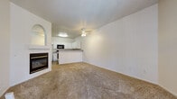 This single-floor residence offers a well-organized layout designed for comfortable everyday living. The open living area is bright and spacious, featuring warm neutral carpet, a ceiling fan with light fixture, and a classic fireplace framed by an arched accent — an inviting focal point for the room. The space flows naturally toward a breakfast bar that separates the living area from the kitchen.

The kitchen is well-appointed with crisp white cabinetry, granite-style countertops, wood-look flooring, and a full suite of appliances including a gas range, over-the-range microwave, and refrigerator. A sink is conveniently positioned at the peninsula counter.

The bedrooms are carpeted and filled with natural light, each featuring ceiling fans and ample closet space. One bedroom includes mirrored sliding closet doors, adding a sense of depth to the room. The entryway is welcoming, with tile flooring at the front door and vertical blinds framing a decorative arched window.

The bathroom includes a full tub-shower combination with white tile surround, white cabinetry with brushed nickel hardware, granite-style countertops, and a large vanity mirror with overhead lighting. A dedicated laundry room with hardwood-style flooring houses a full-size washer and dryer and provides additional shelving for storage.