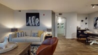 This single-floor residence offers a thoughtfully designed layout that balances comfort and functionality across its key living spaces. The living room serves as the heart of the unit, featuring rich wood-look flooring, neutral gray walls, and an arched doorway that adds an elegant architectural detail. Bold abstract artwork accentuates the space, while a ceiling fan overhead provides practical comfort in the adjoining sitting area, which opens to a sliding glass door for natural light.

The galley-style kitchen is efficient and stylish, featuring white shaker cabinetry with brushed nickel hardware, dark countertops, wood-look flooring, and stainless steel appliances. Adjacent to the kitchen, a dedicated dining area with track lighting provides a welcoming space for meals.

The primary bedroom is generously sized with plush carpet, a large window with blinds, a ceiling fan, and curated wall art. The second bedroom mirrors this comfortable aesthetic with soft carpet and ample natural light. The bathroom is finished with white cabinetry, dark countertops, wood-look flooring, and a shower-tub combination with a decorative curtain.

Throughout the unit, a cohesive color palette of warm neutrals and cool grays creates a calm, modern ambiance well-suited for everyday living.